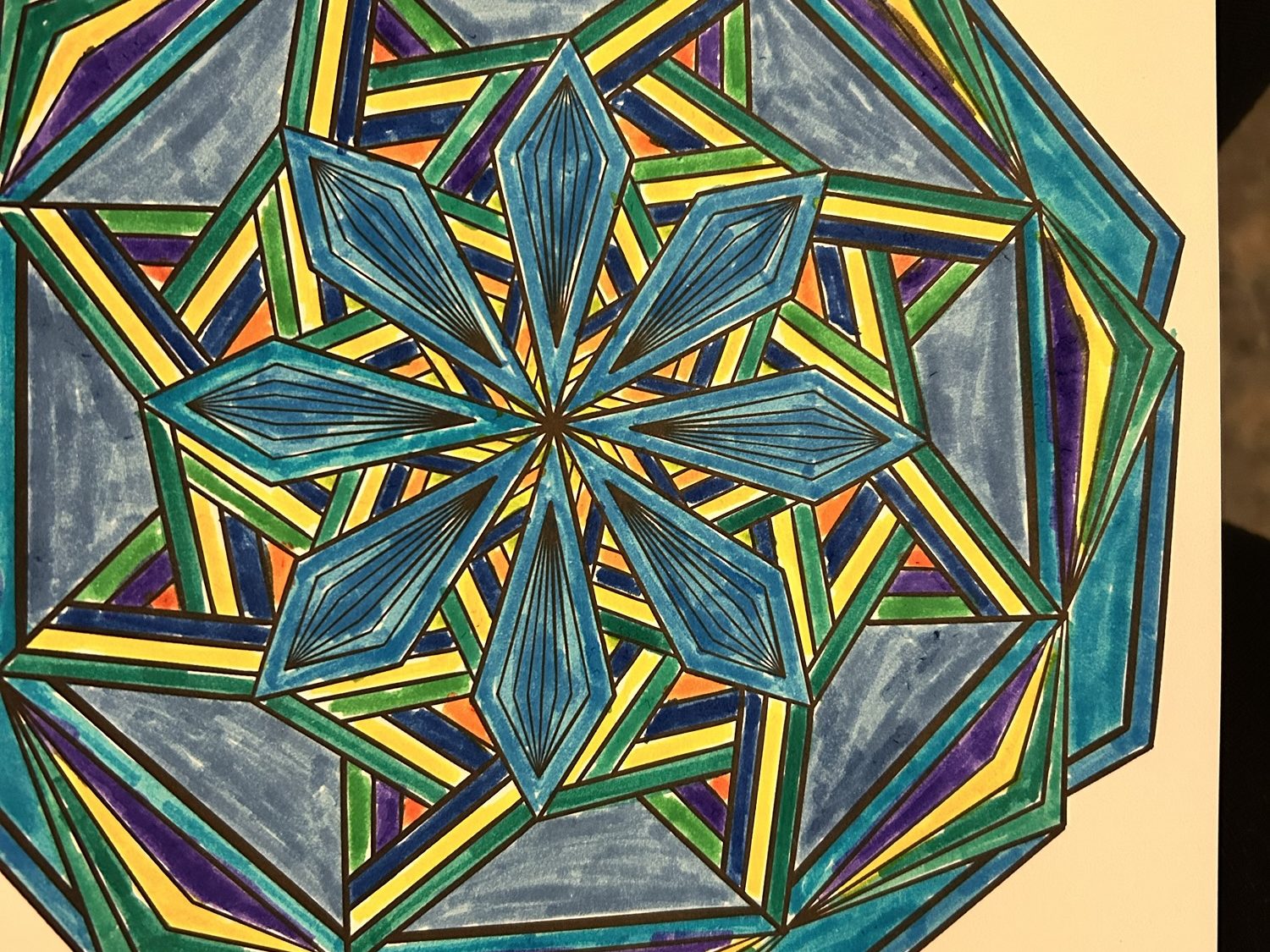A colorful mandala coloring page featuring geometric shapes in shades of blue, green, yellow, and purple.